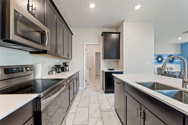 kitchen with decorative backsplash, dark brown cabinets, stainless steel appliances, and sink