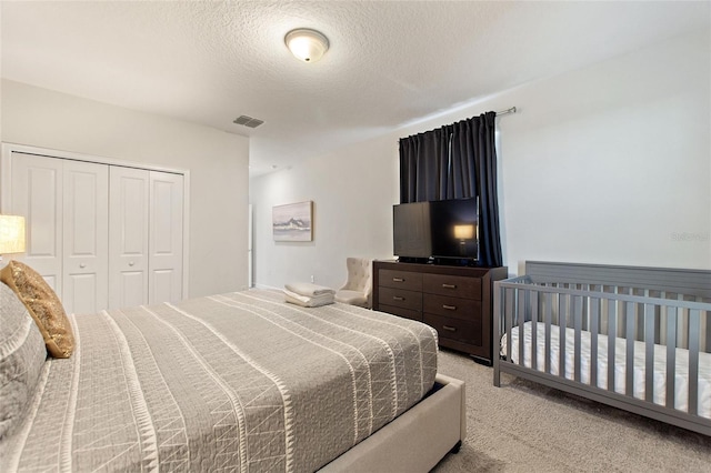 bedroom featuring a textured ceiling, light colored carpet, and a closet