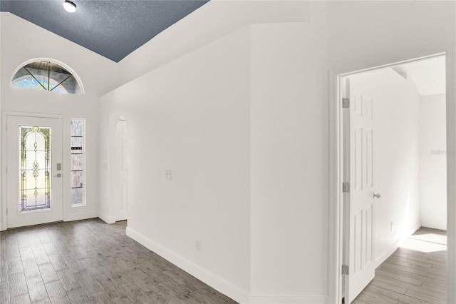 entrance foyer featuring hardwood / wood-style flooring, lofted ceiling, and a textured ceiling