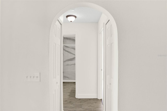 corridor with hardwood / wood-style floors and a textured ceiling