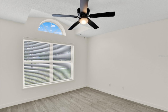 empty room featuring a textured ceiling, ceiling fan, light hardwood / wood-style floors, and lofted ceiling