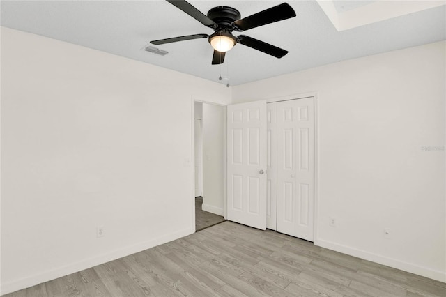 unfurnished bedroom featuring ceiling fan, light wood-type flooring, and a closet