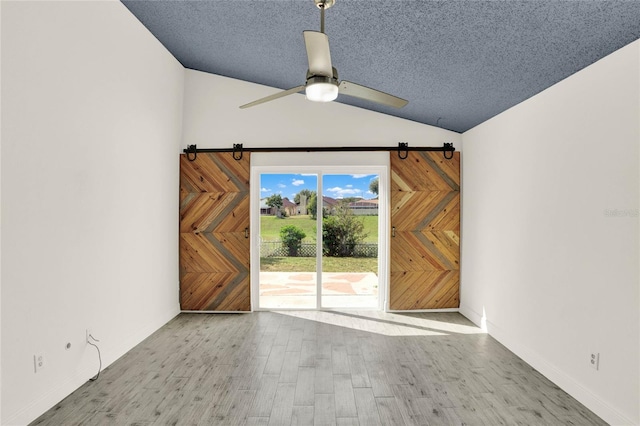 spare room featuring a textured ceiling, light hardwood / wood-style flooring, vaulted ceiling, and ceiling fan