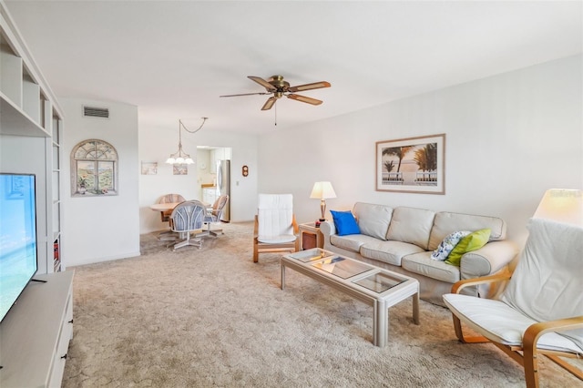 living room with ceiling fan with notable chandelier and light colored carpet