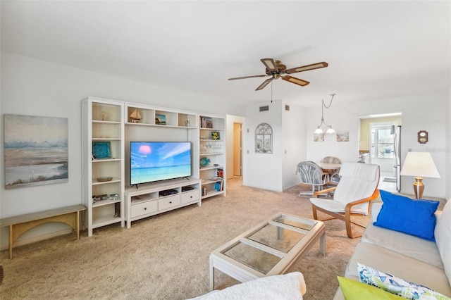 carpeted living room with ceiling fan with notable chandelier