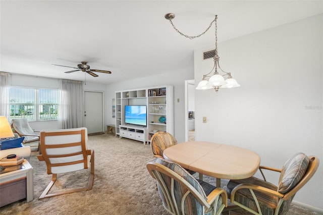 carpeted dining area featuring ceiling fan with notable chandelier