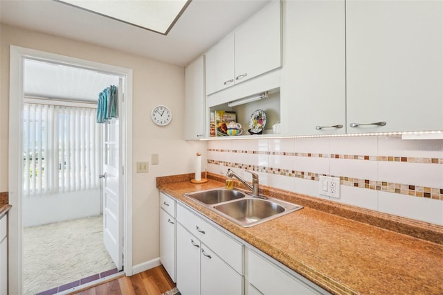 kitchen with white cabinetry, sink, tasteful backsplash, and light wood-type flooring