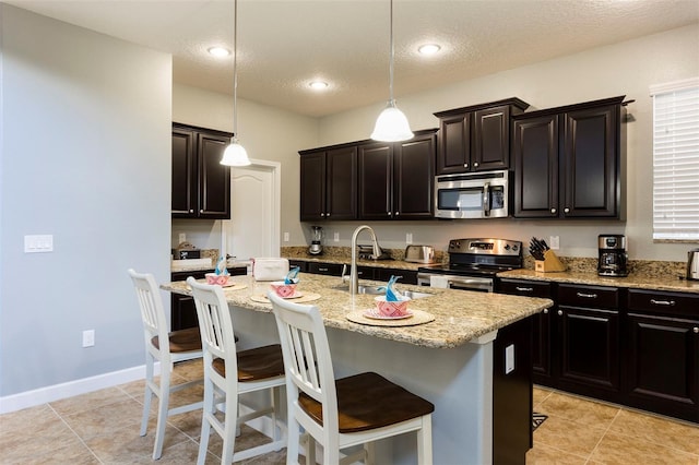 kitchen with pendant lighting, a center island with sink, stainless steel appliances, and sink