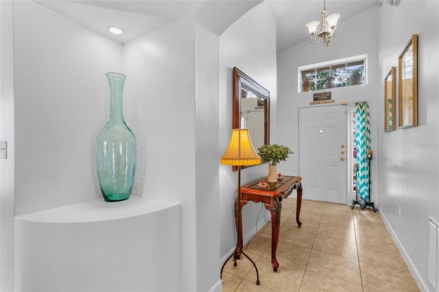 foyer with light tile patterned floors, a chandelier, and lofted ceiling