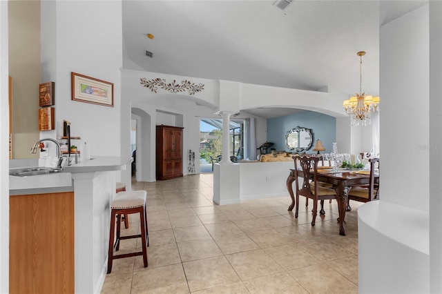 tiled dining space featuring lofted ceiling, sink, and a chandelier