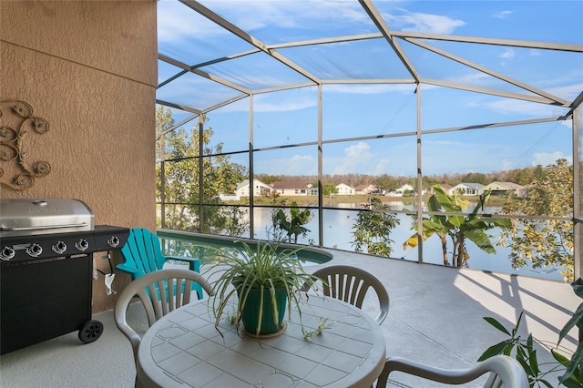 view of patio / terrace featuring a lanai, a water view, and grilling area