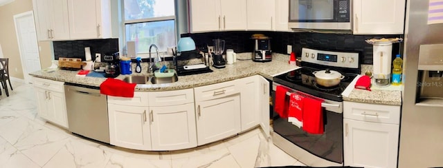 kitchen featuring appliances with stainless steel finishes, tasteful backsplash, light stone counters, sink, and white cabinets