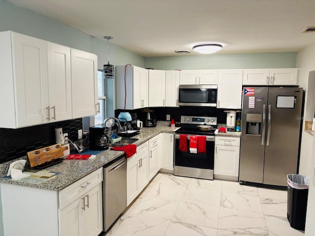 kitchen with sink, backsplash, pendant lighting, white cabinets, and appliances with stainless steel finishes