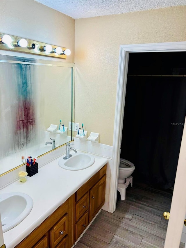 bathroom with a textured ceiling, vanity, and toilet