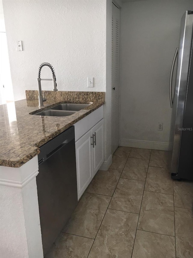 kitchen featuring white cabinets, sink, stainless steel fridge, dark stone countertops, and black dishwasher