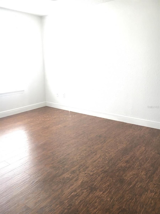 empty room with dark hardwood / wood-style floors and a healthy amount of sunlight