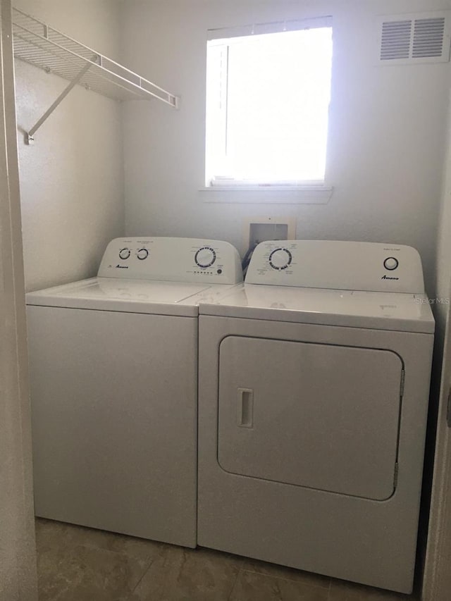 laundry area with dark tile patterned floors and washing machine and clothes dryer