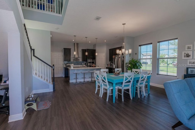 dining room with sink, dark hardwood / wood-style flooring, and an inviting chandelier