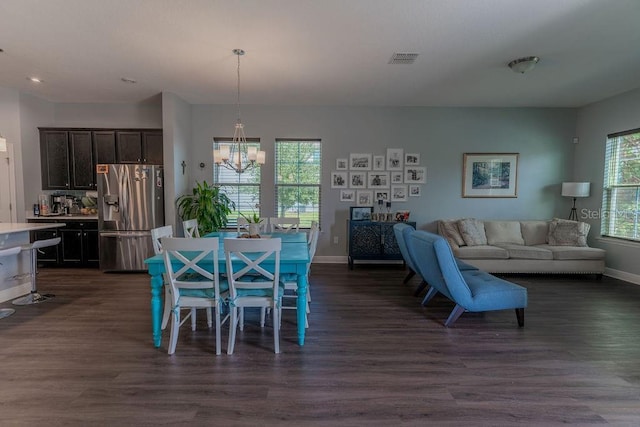 dining room featuring a healthy amount of sunlight, dark hardwood / wood-style floors, and an inviting chandelier