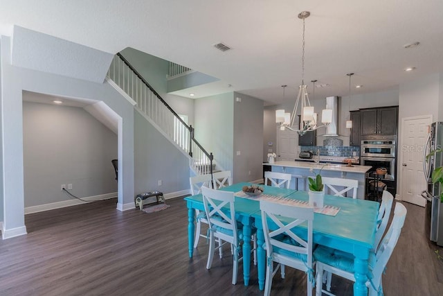 dining area with dark wood-type flooring and an inviting chandelier