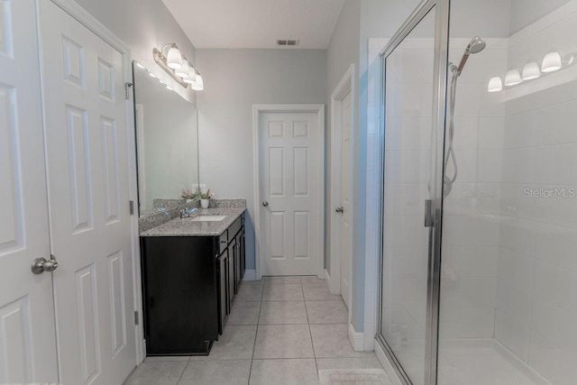 bathroom with a shower with door, vanity, and tile patterned flooring