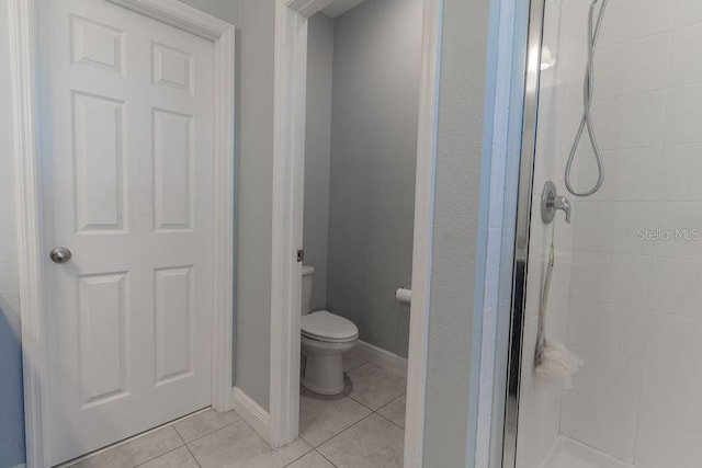 bathroom with toilet, tile patterned flooring, and a shower with door