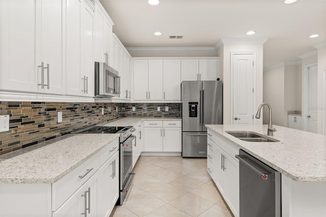 kitchen with decorative backsplash, appliances with stainless steel finishes, a kitchen island with sink, sink, and white cabinets