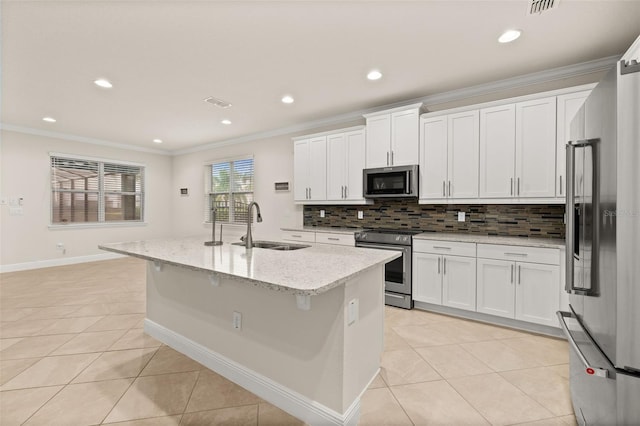 kitchen featuring white cabinets, appliances with stainless steel finishes, light stone counters, and an island with sink