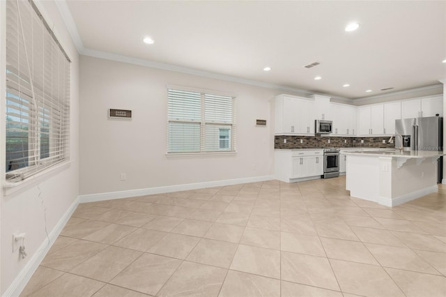 kitchen featuring a kitchen bar, stainless steel appliances, a kitchen island with sink, crown molding, and white cabinetry