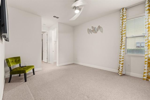 living area featuring a wealth of natural light, ceiling fan, and light colored carpet