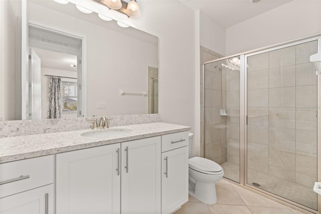 bathroom featuring toilet, vanity, tile patterned floors, and a shower with shower door