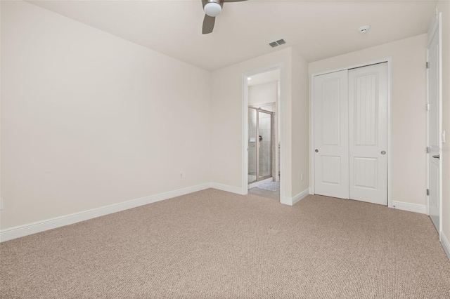 unfurnished bedroom with light carpet, a closet, ensuite bath, and ceiling fan