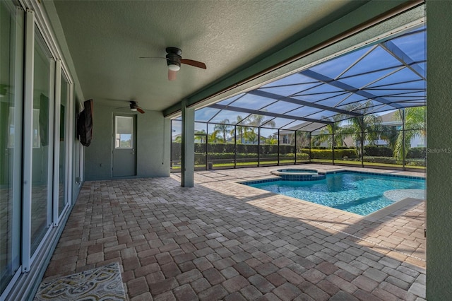 view of swimming pool with glass enclosure, ceiling fan, a patio area, and an in ground hot tub