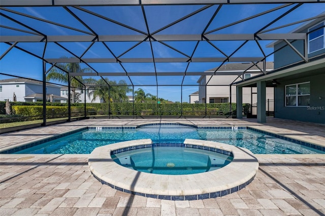 view of swimming pool with glass enclosure, a patio area, and an in ground hot tub