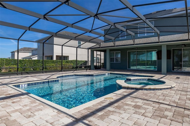 view of swimming pool with ceiling fan, a patio area, an in ground hot tub, and glass enclosure