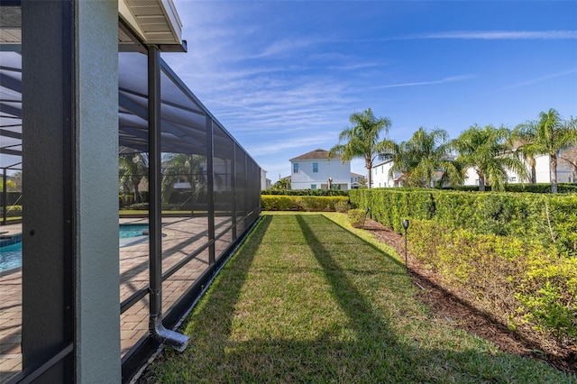 view of yard with a fenced in pool and glass enclosure