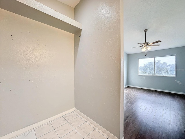 empty room with ceiling fan and a textured ceiling