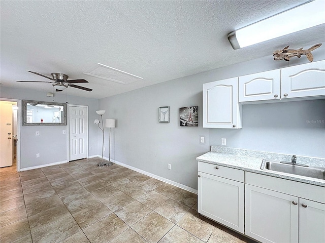 kitchen with white cabinetry, sink, ceiling fan, and a textured ceiling