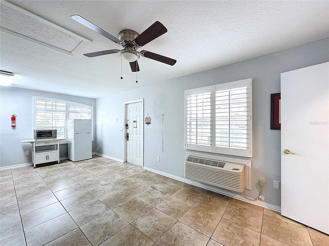 interior space with light tile patterned floors, a textured ceiling, an AC wall unit, and ceiling fan