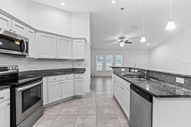 kitchen with sink, stainless steel appliances, dark stone countertops, decorative light fixtures, and white cabinets