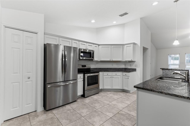 kitchen with stainless steel appliances, sink, dark stone countertops, white cabinets, and hanging light fixtures