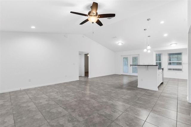 unfurnished living room featuring ceiling fan, french doors, and vaulted ceiling