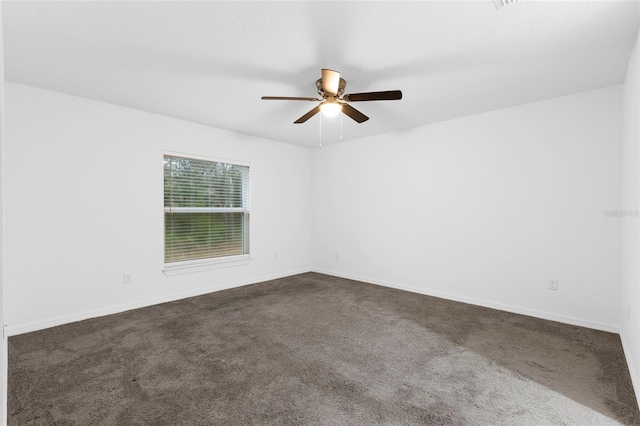 spare room with dark colored carpet and ceiling fan