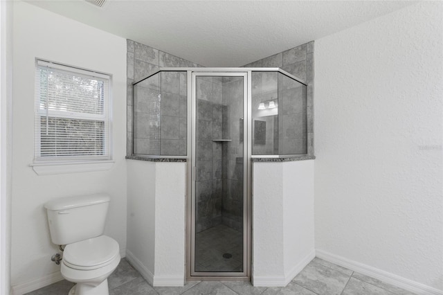 bathroom with tile patterned flooring, a textured ceiling, toilet, and a shower with shower door