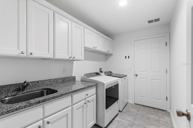 clothes washing area featuring cabinets, light tile patterned floors, washing machine and clothes dryer, and sink