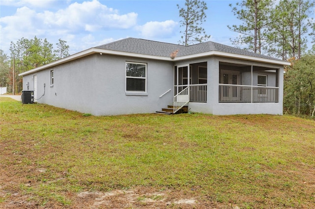 back of house featuring central AC unit, a sunroom, and a lawn