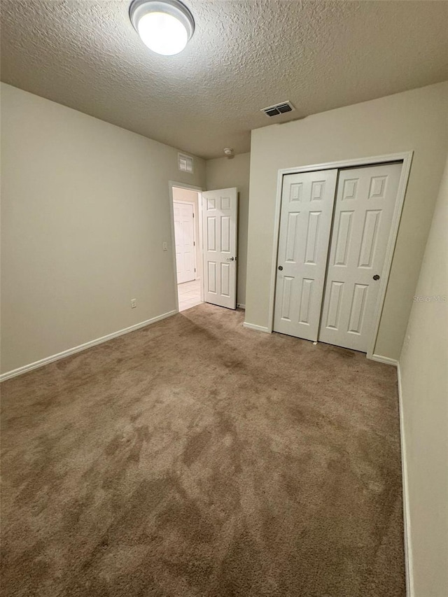 unfurnished bedroom with carpet, a textured ceiling, and a closet