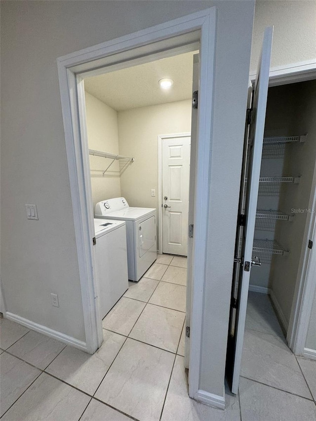 laundry area featuring washing machine and clothes dryer and light tile patterned floors