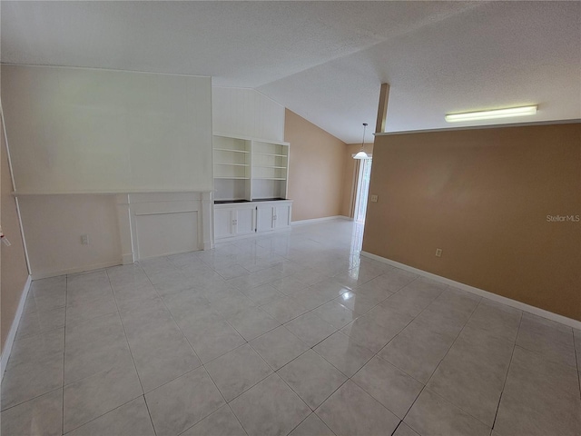 tiled empty room with built in shelves, lofted ceiling, and a textured ceiling