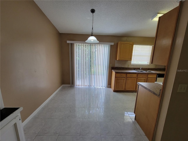 kitchen with backsplash, a textured ceiling, sink, light tile patterned floors, and decorative light fixtures